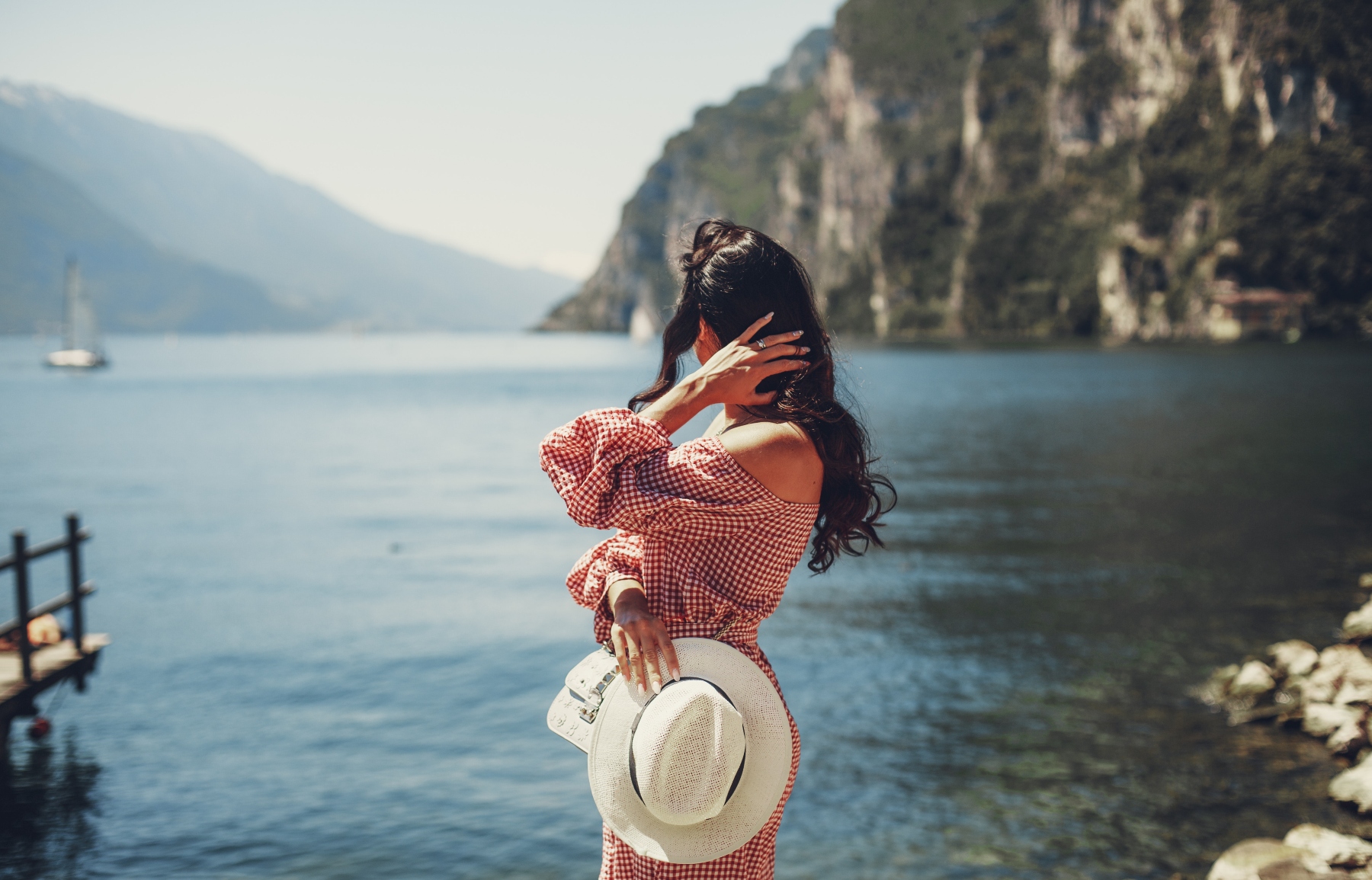 girl holding hat and looking at the sea