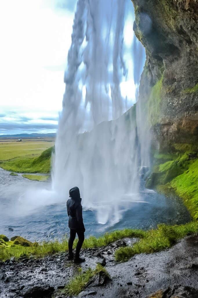 standing in front of a very tall waterfall