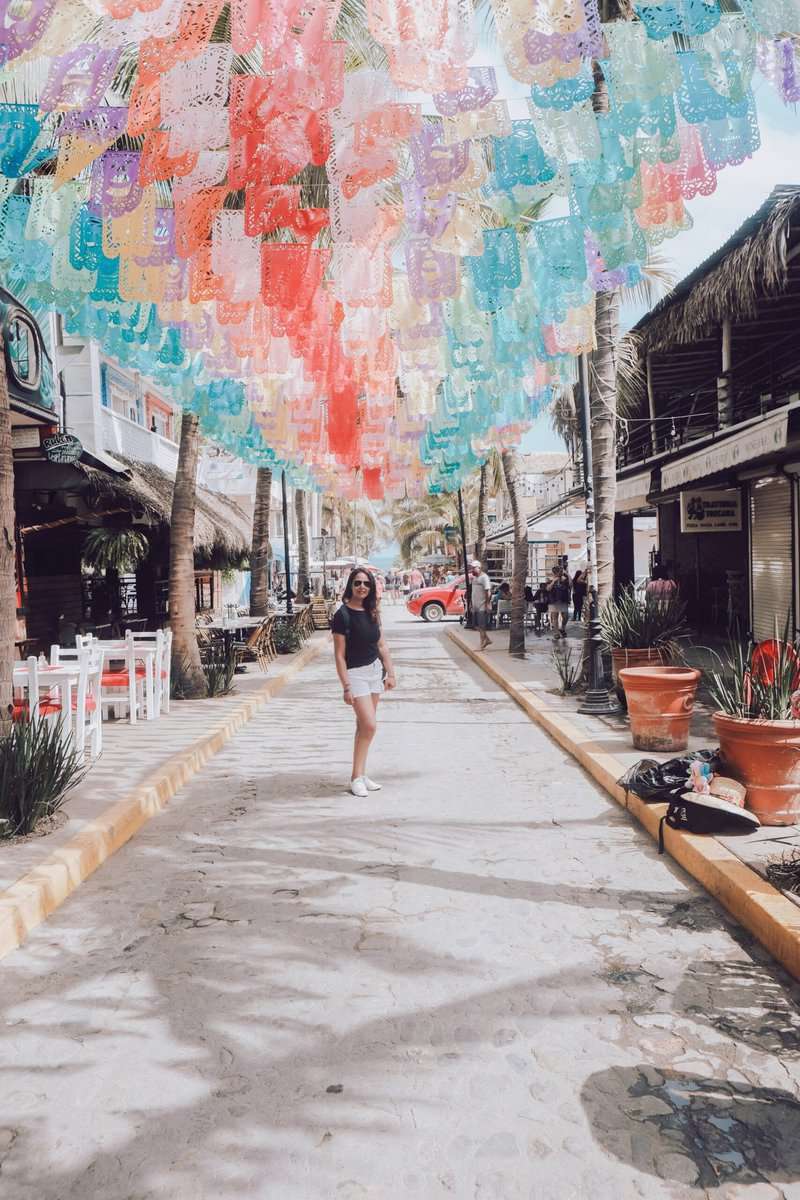 A woman strolling amidst vibrant paper lanterns on a street.