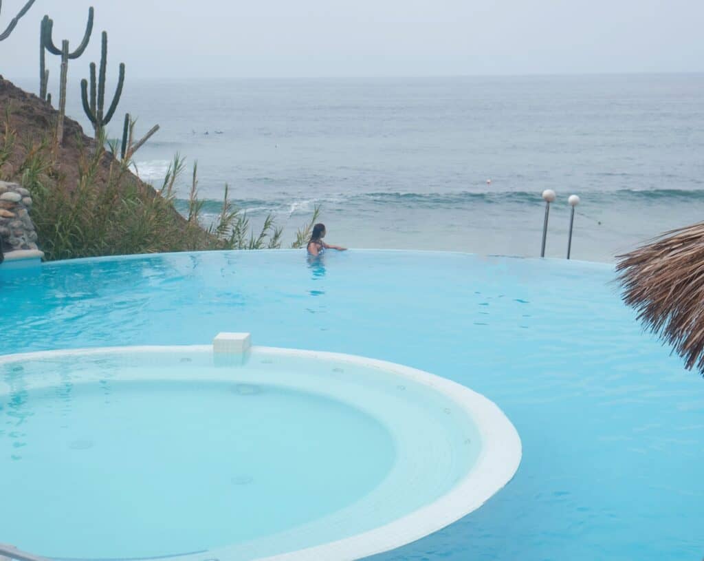 Girl sitting in the blue infinity pool looking at the ocean at Grand Palladium puerto vallarta