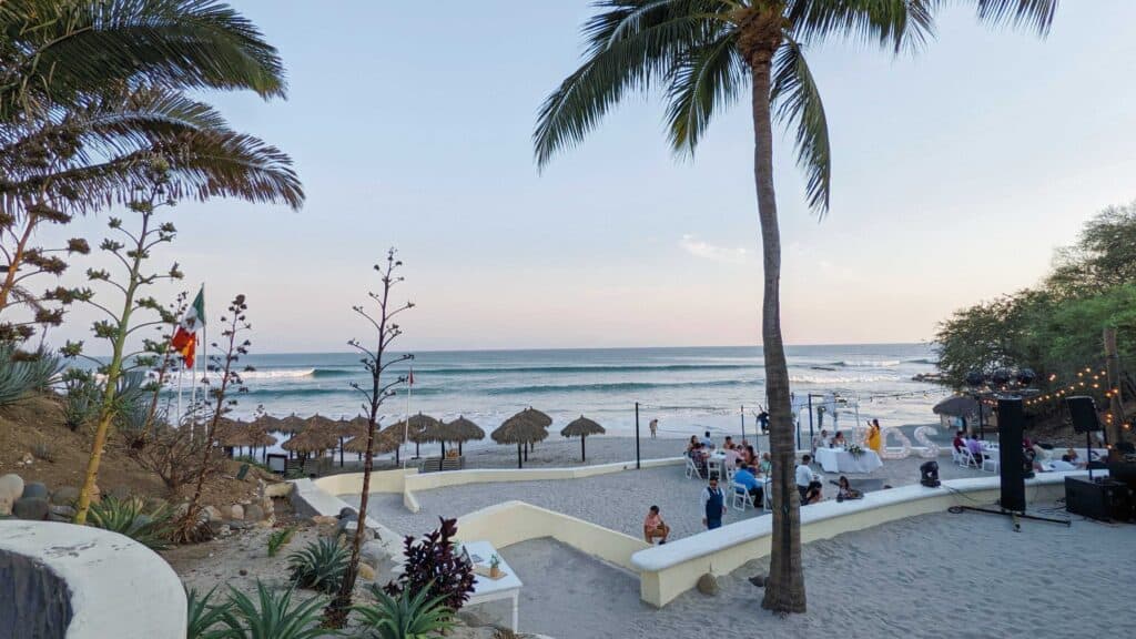 Calm beach and palm trees and people celebrating a wedding at the Grand Palladium puerto vallarta