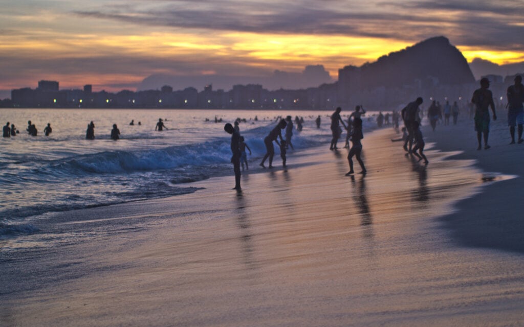 beautiful sunset, people swimming in sandy beach