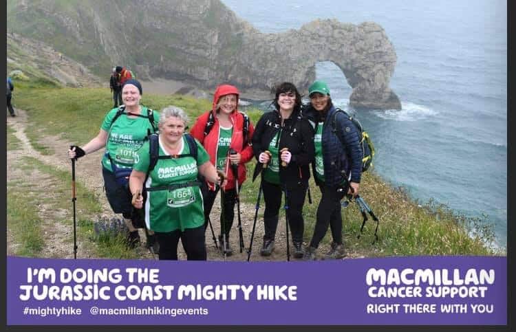 a group of women smiling with the durdle door view as a backdrop