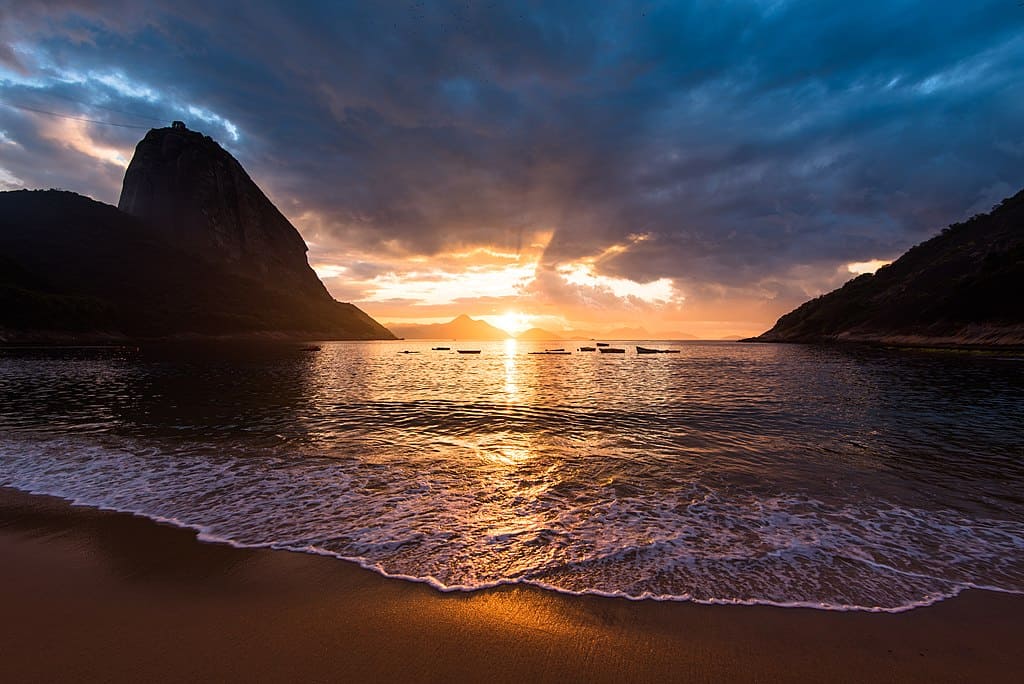 Spectacular sunset, golden blue sky and a mountain silhouette on one of the most beautiful beaches in rio de janeiro