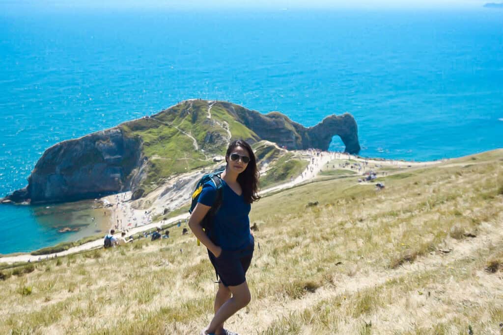Girl standing on a hill with backdrop of Durdle door view