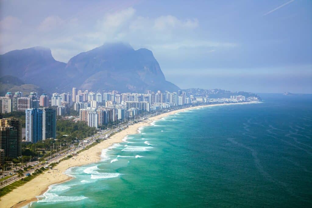 A wide green beach with high rise condos and mountains in the background