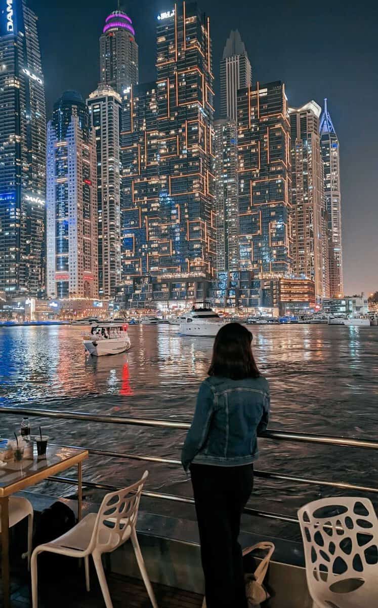 girl on a boat looking at a skyline at night time